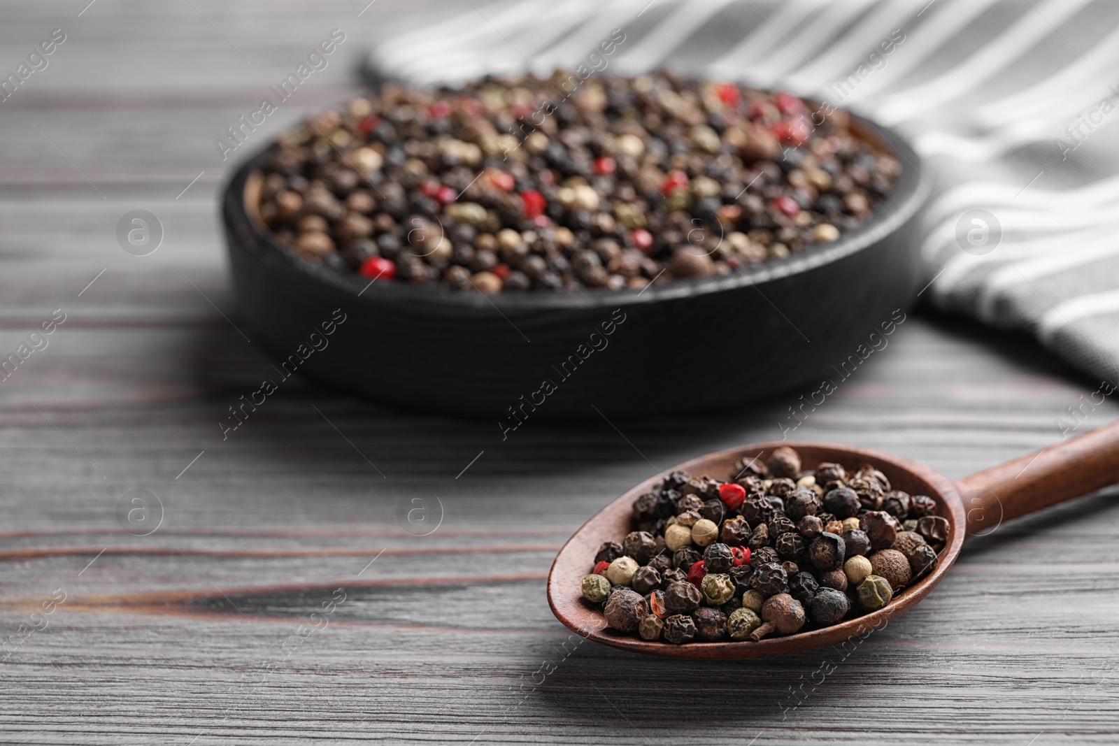 Photo of Different peppercorns on light grey wooden table, closeup