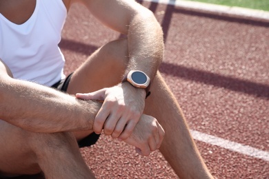 Man with fitness tracker after training at stadium, closeup