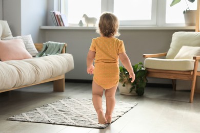 Cute baby learning to walk in living room