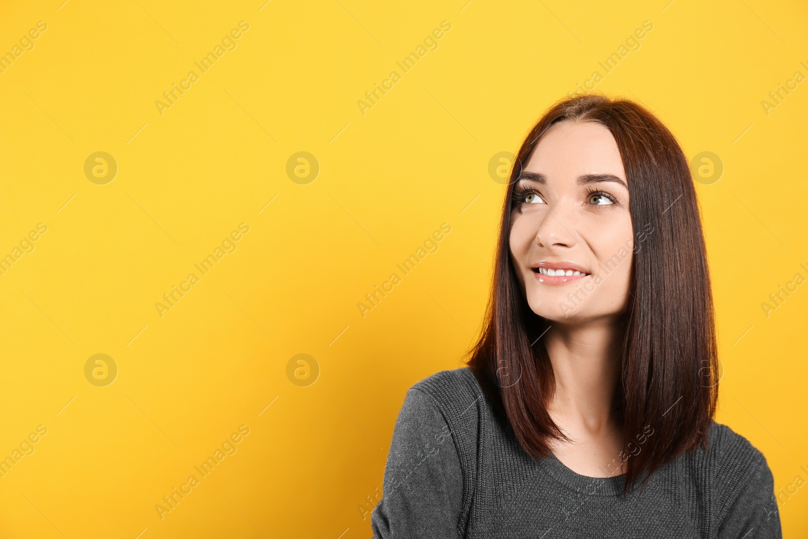 Photo of Portrait of pretty young woman with gorgeous chestnut hair and charming smile on yellow background, space for text