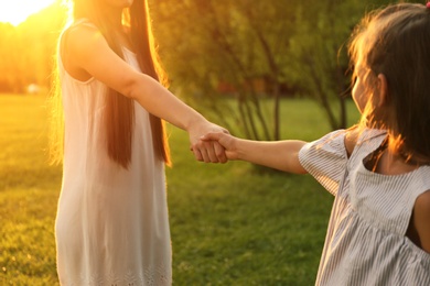 Little girl holding hands with her mother in park. Happy family