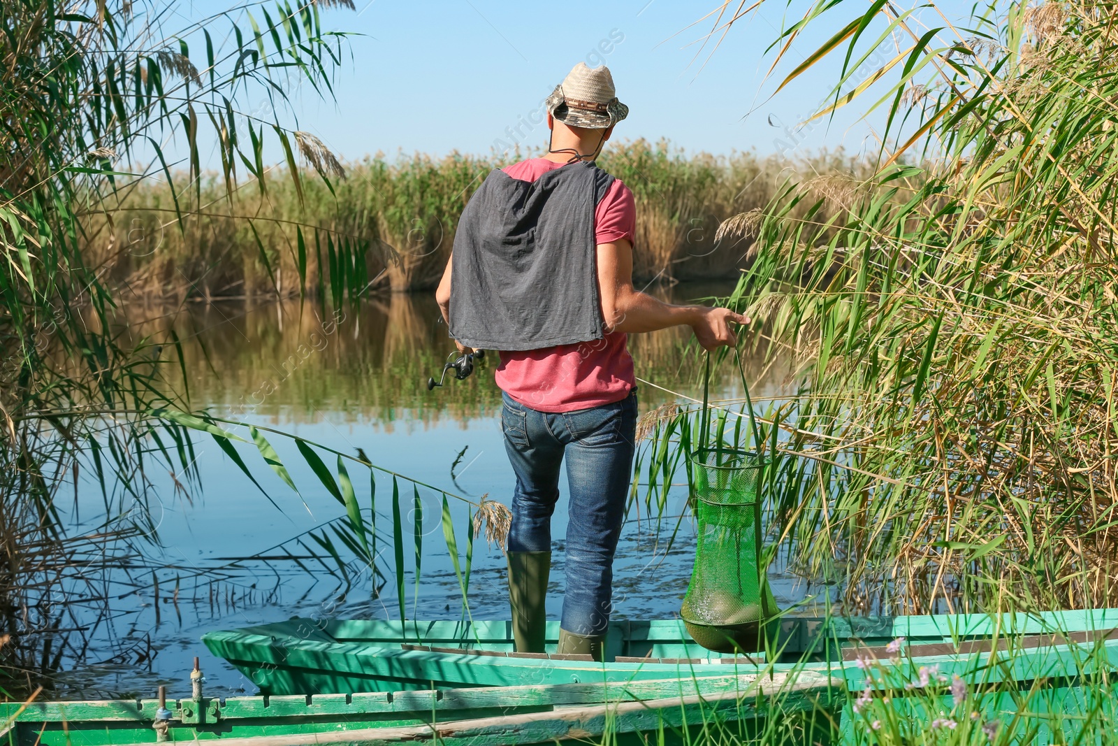 Photo of Young man fishing from boat on sunny day