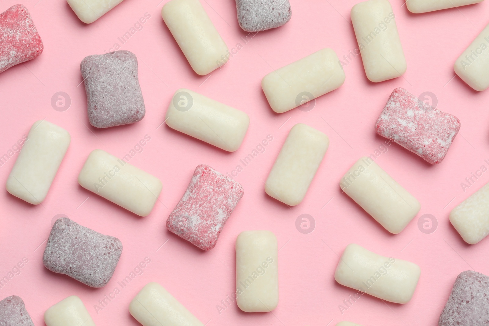 Photo of Different tasty colorful bubble gums on pink background, flat lay