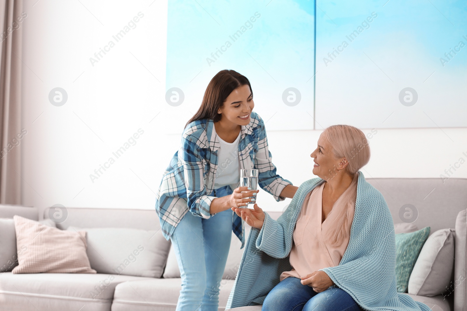 Photo of Daughter giving glass of water to her mother at home. Help concept