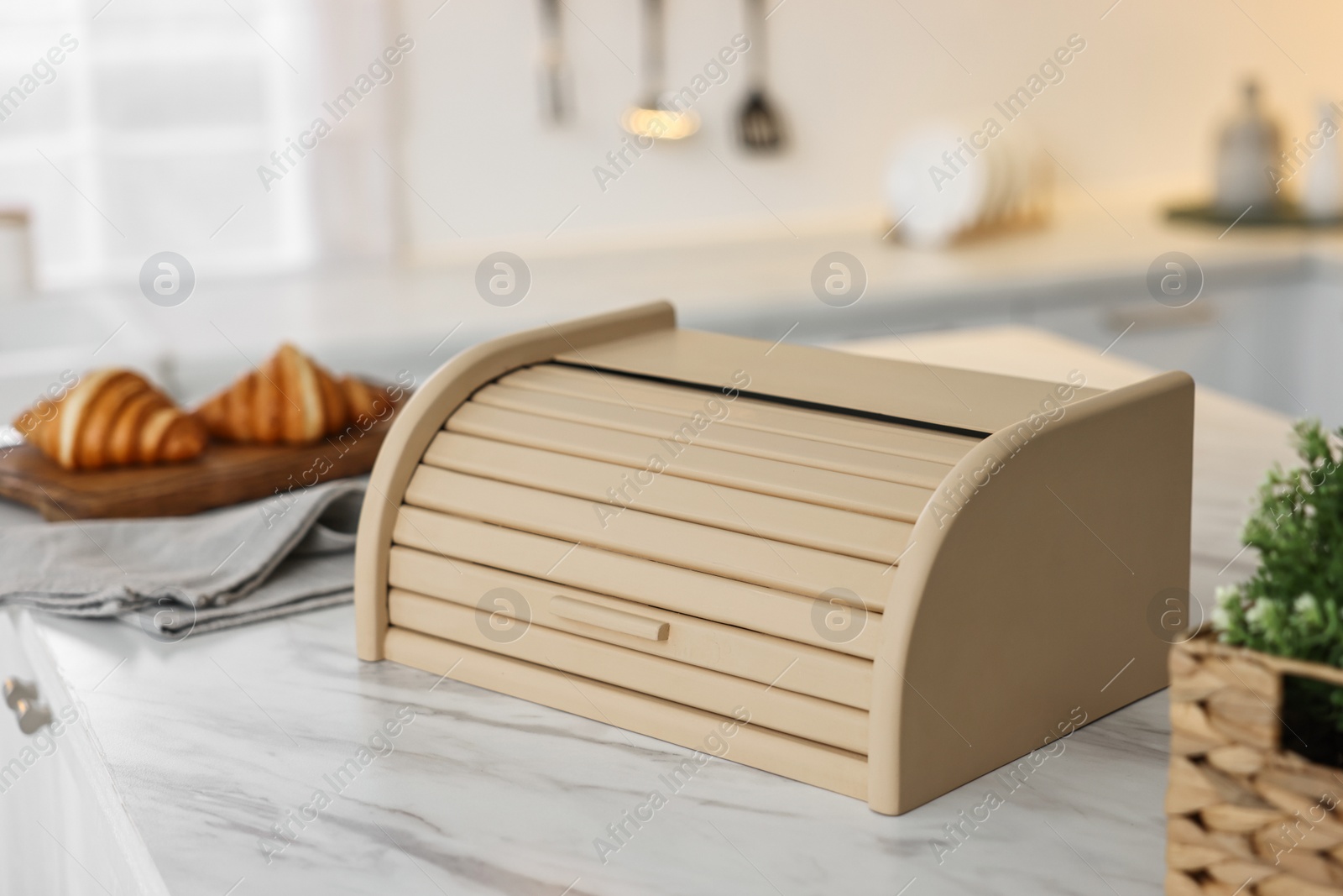 Photo of Wooden bread box on white marble table in kitchen