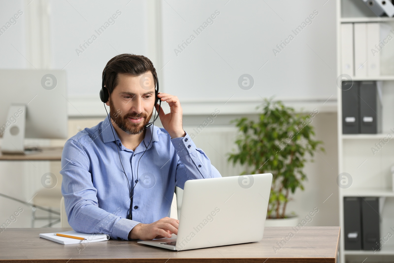 Photo of Hotline operator with headset working in office