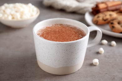 Cup of delicious hot cocoa on grey table