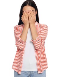 Embarrassed young woman covering face with hands on white background