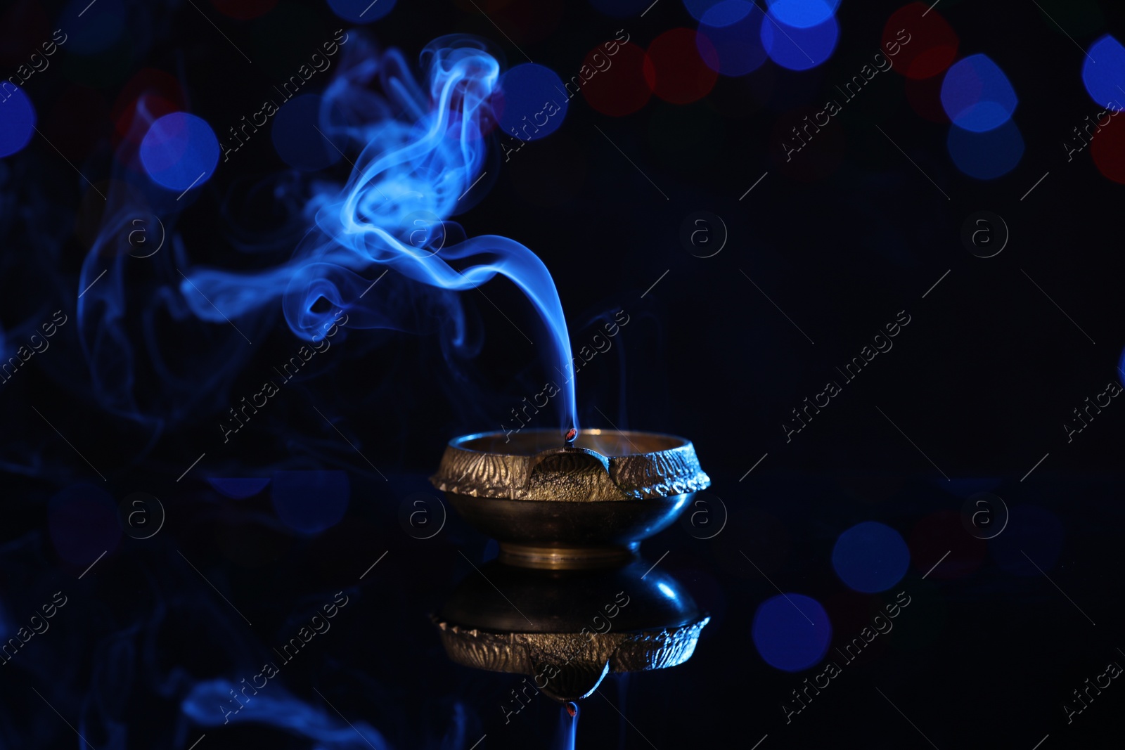 Photo of Blown out diya on dark background with blurred lights. Diwali lamp