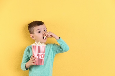 Photo of Cute little boy with popcorn on color background. Space for text