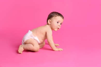 Photo of Cute baby in dry soft diaper crawling on pink background