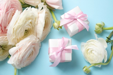 Photo of Beautiful ranunculus flowers and gift boxes on color background, view from above