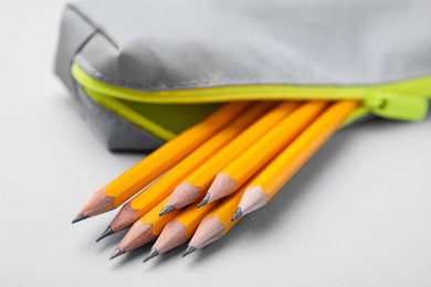 Photo of Many sharp pencils in pencil case on light grey background, closeup