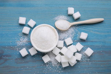 Photo of Different types of white sugar on light blue wooden table, flat lay