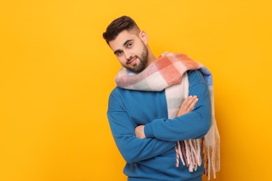 Handsome man in warm scarf on yellow background. Space for text