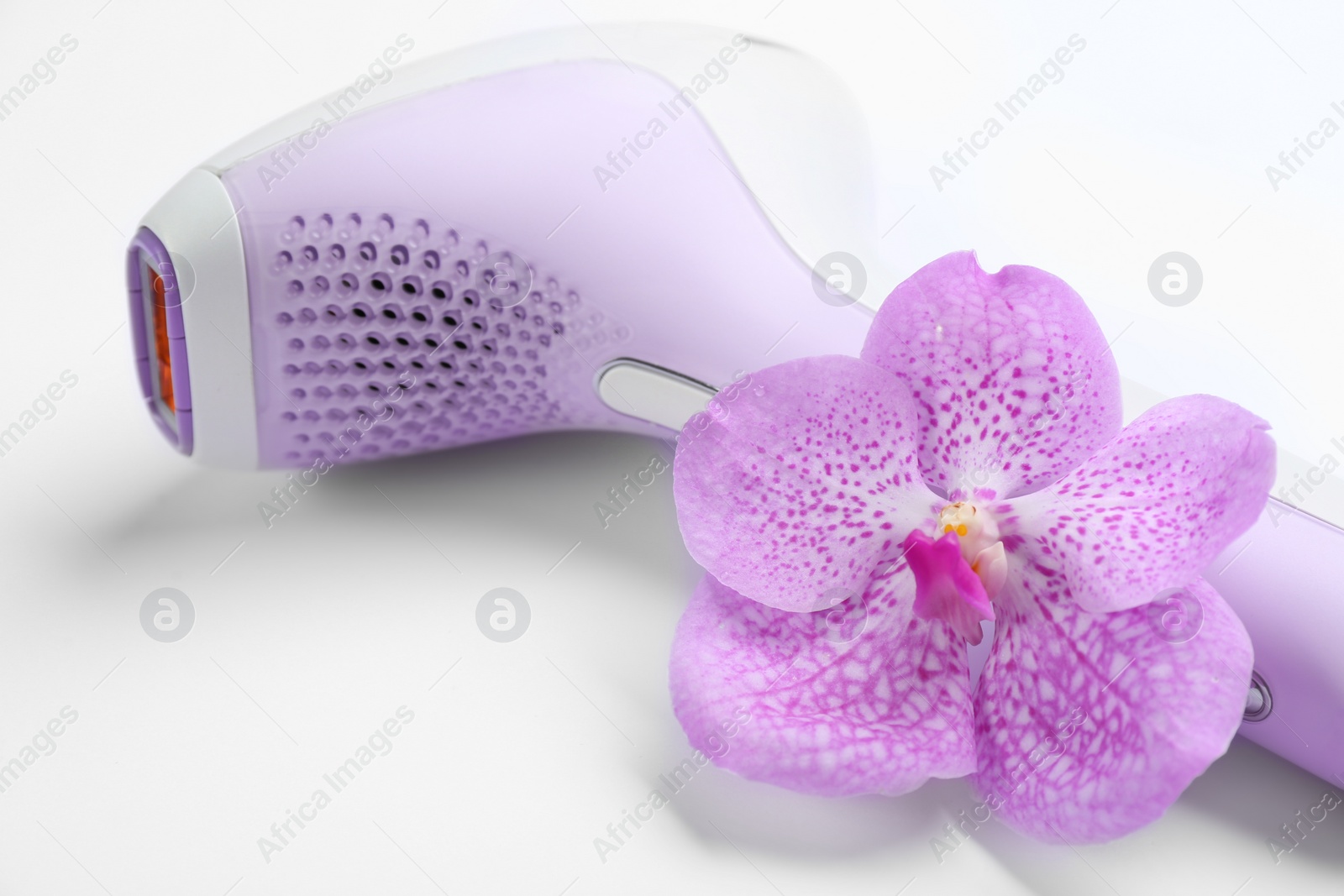 Image of Modern photoepilator and orchid flower on white background, closeup