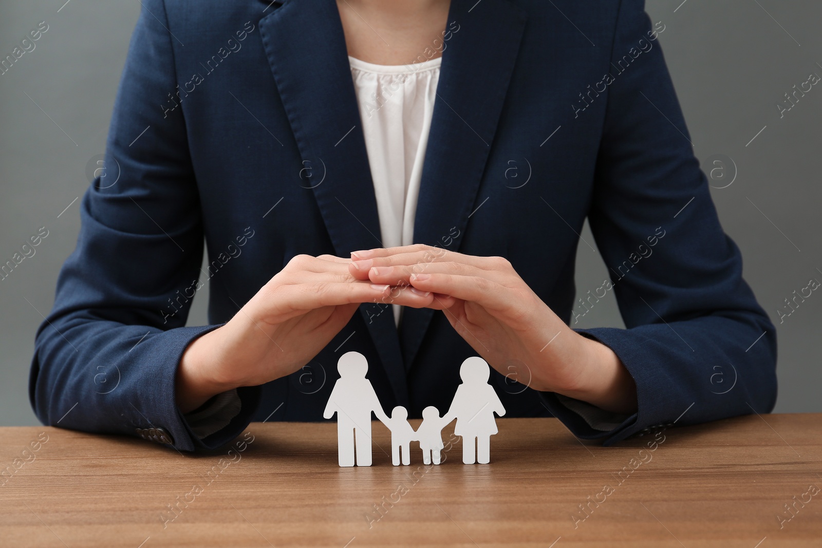 Photo of Woman covering cutout paper family at table, closeup. Life insurance concept