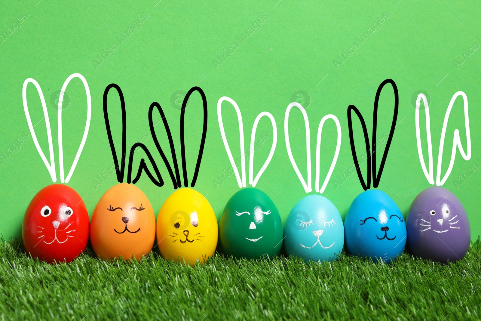 Image of Colorful eggs as Easter bunnies on green grass against color background