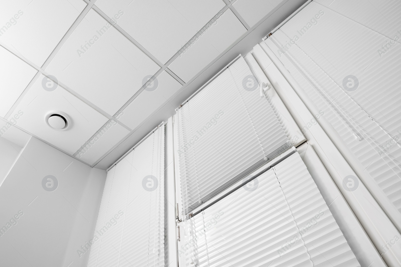 Photo of Window with closed white horizontal blinds indoors, low angle view