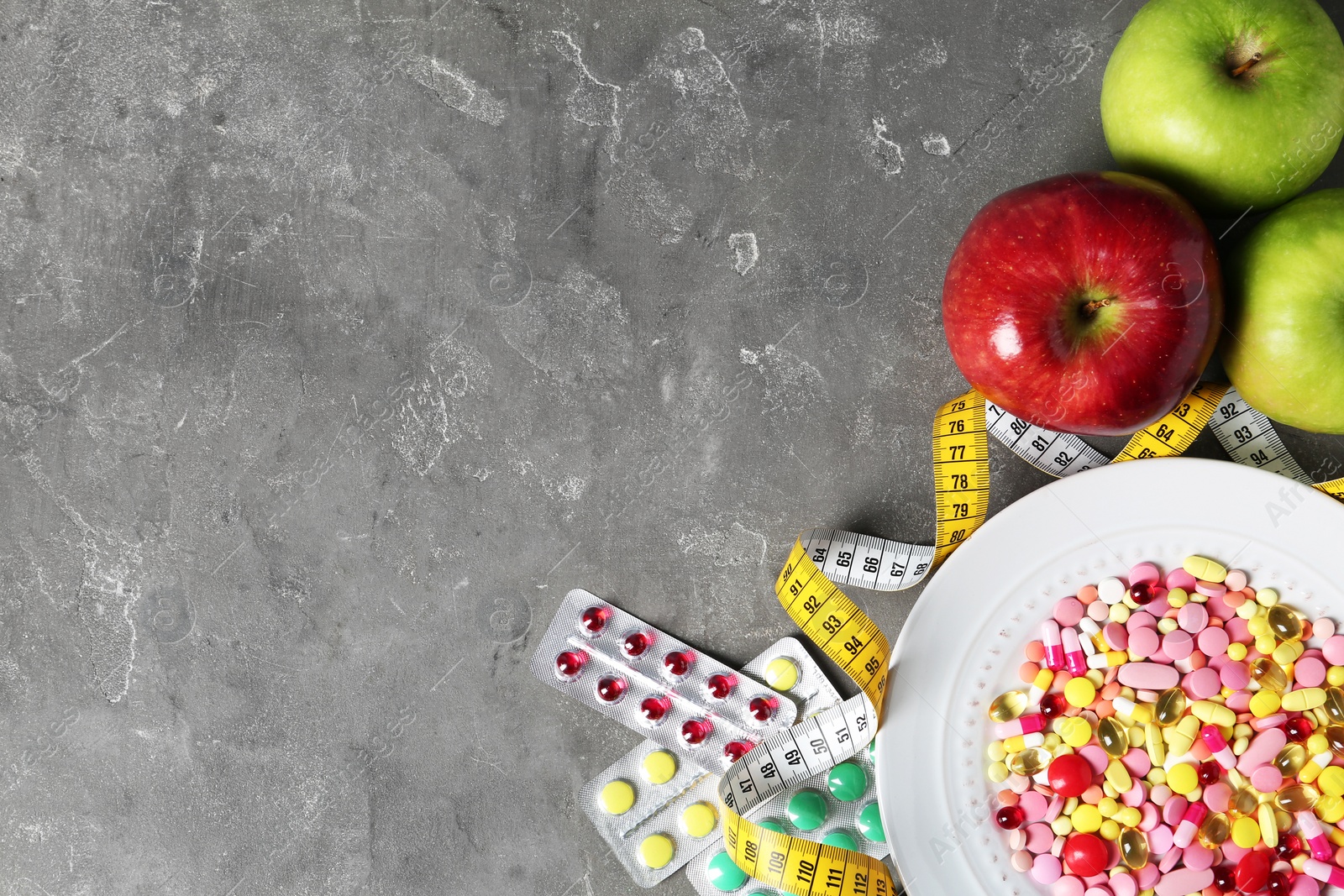 Photo of Flat lay composition with weight loss pills and apples on gray background. Space for text