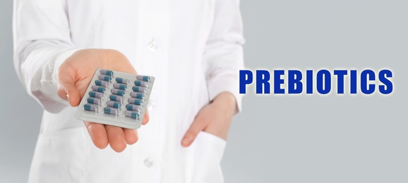 Pharmacist with pills on light grey background, closeup. Prebiotic supplements