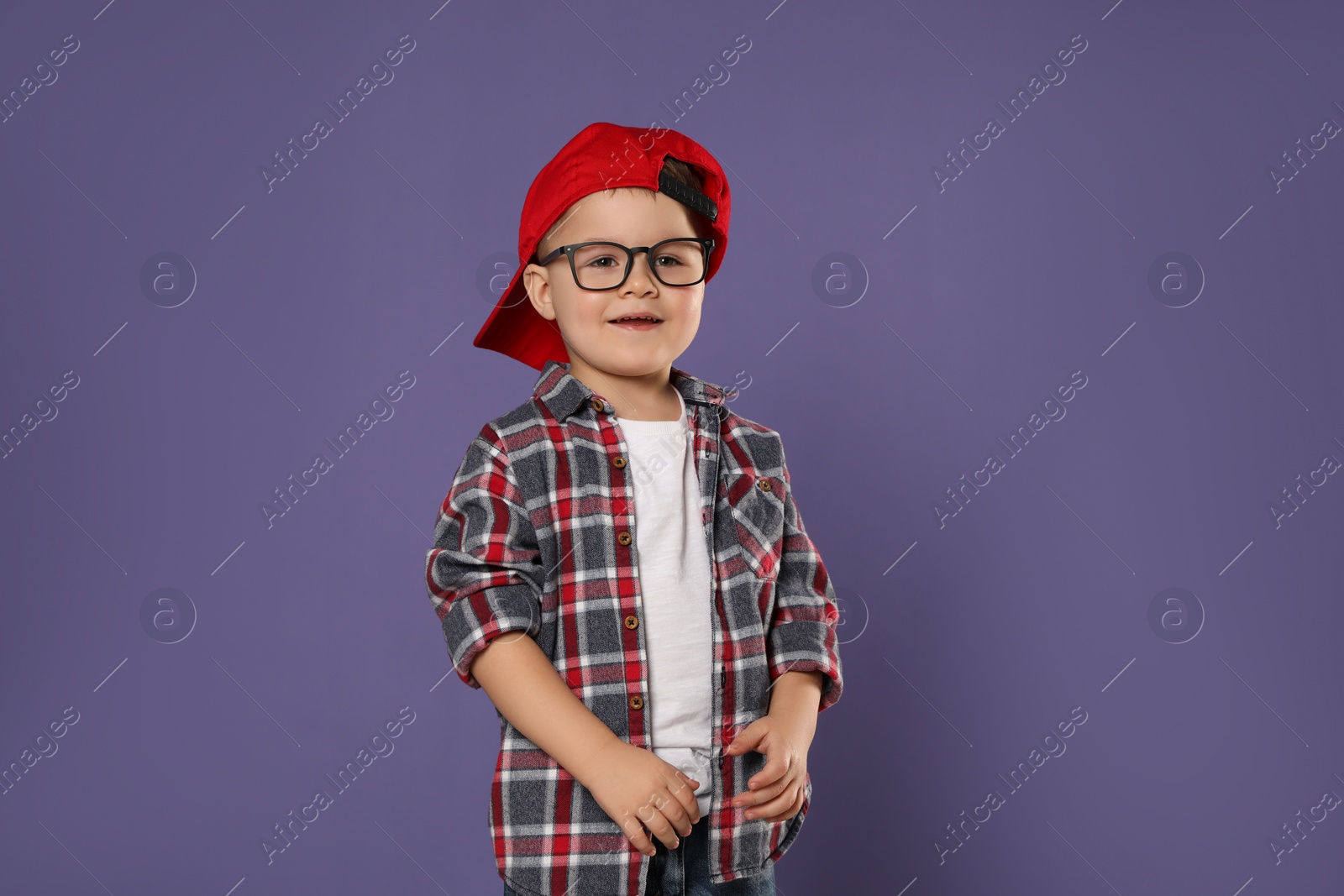 Photo of Cute little boy in glasses on purple background