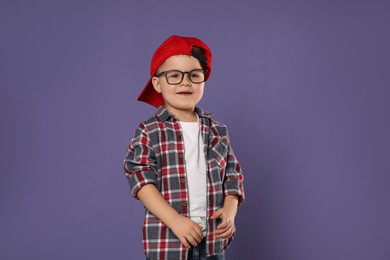 Cute little boy in glasses on purple background