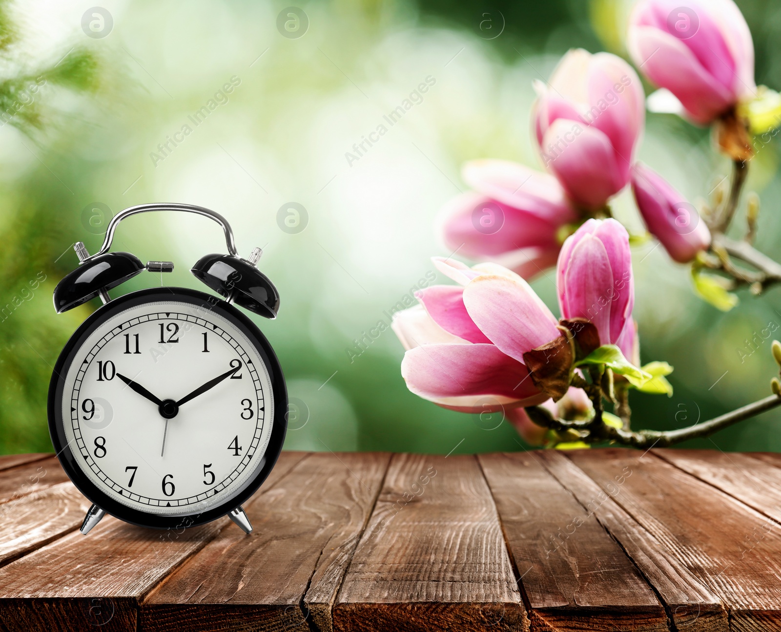 Image of Black alarm clock on wooden table, space for text. Daylight saving time (Spring forward)