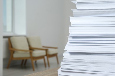 Photo of Stack of paper sheets on wooden table indoors, closeup. Space for text