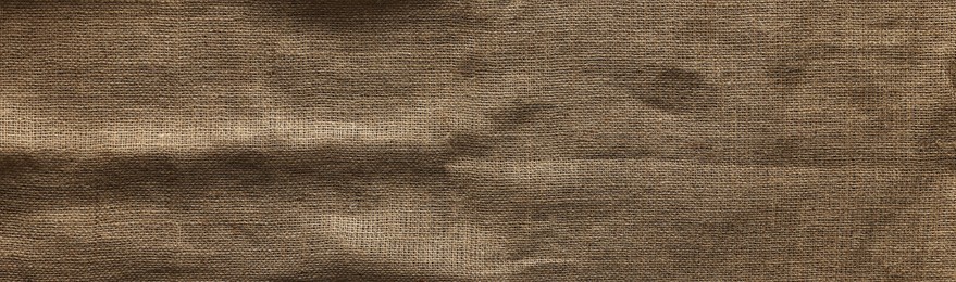 Photo of Burlap fabric on wooden table, top view