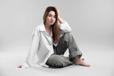 Beautiful young woman sitting on grey background