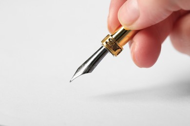 Woman with fountain pen above white paper, closeup