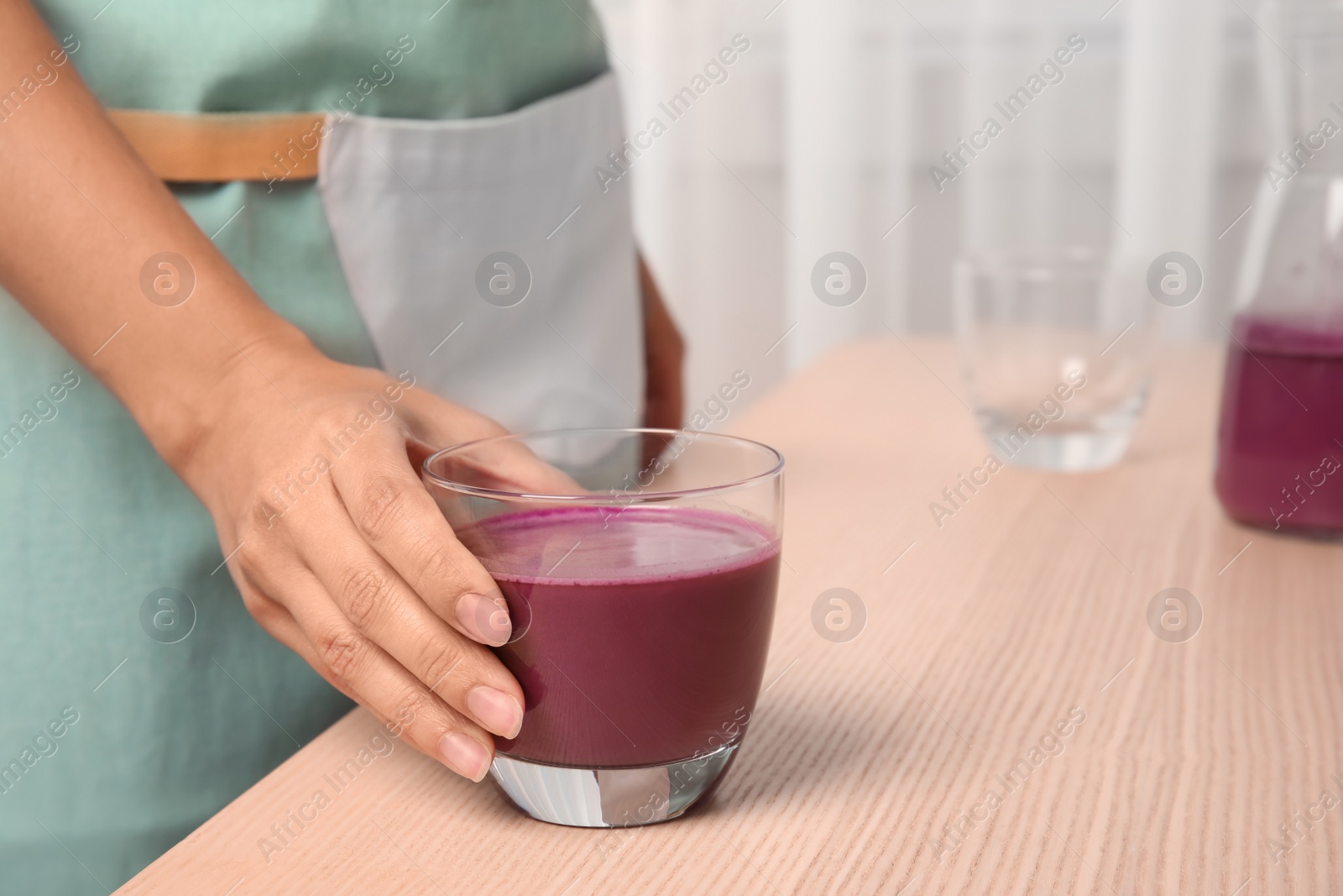 Photo of Woman holding glass of delicious acai juice on table, closeup