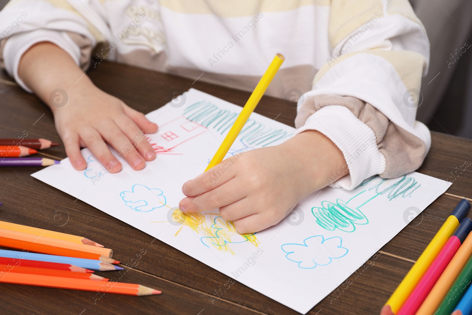 Photo of Little boy drawing with pencil at wooden table, closeup. Child`s art