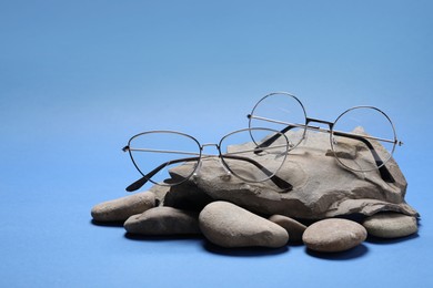 Stylish glasses with metal frames and stones on blue background