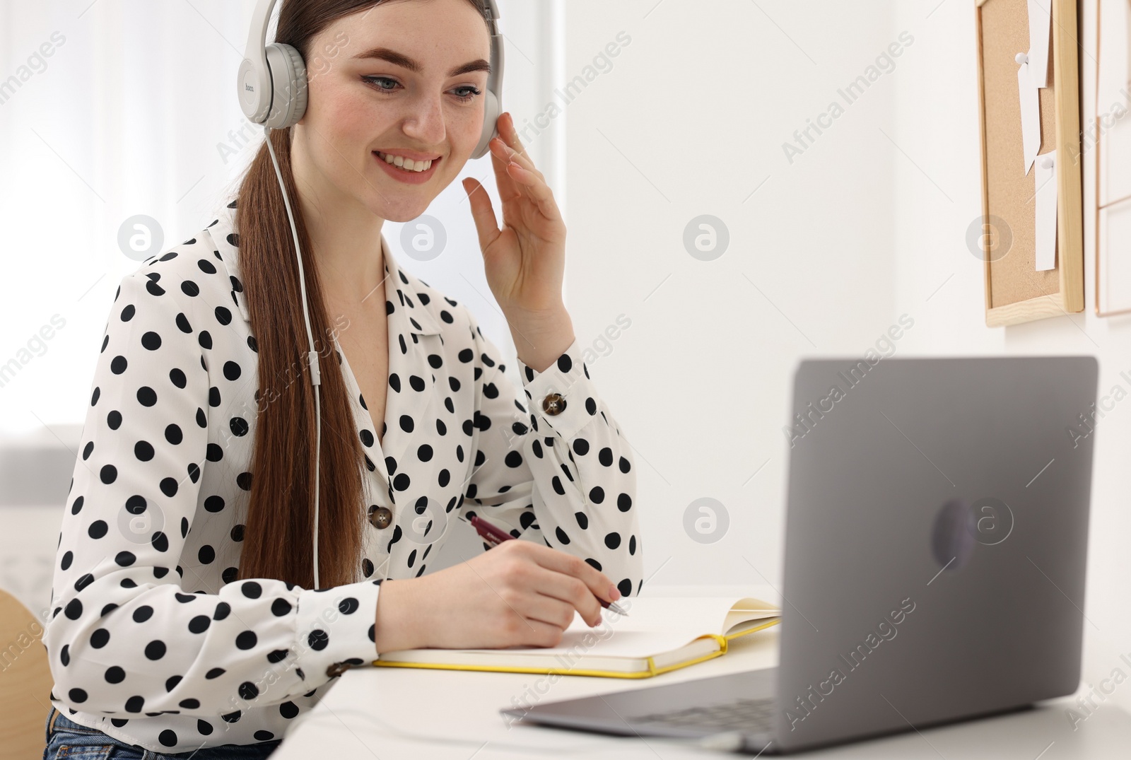 Photo of E-learning. Young woman using laptop during online lesson at table indoors