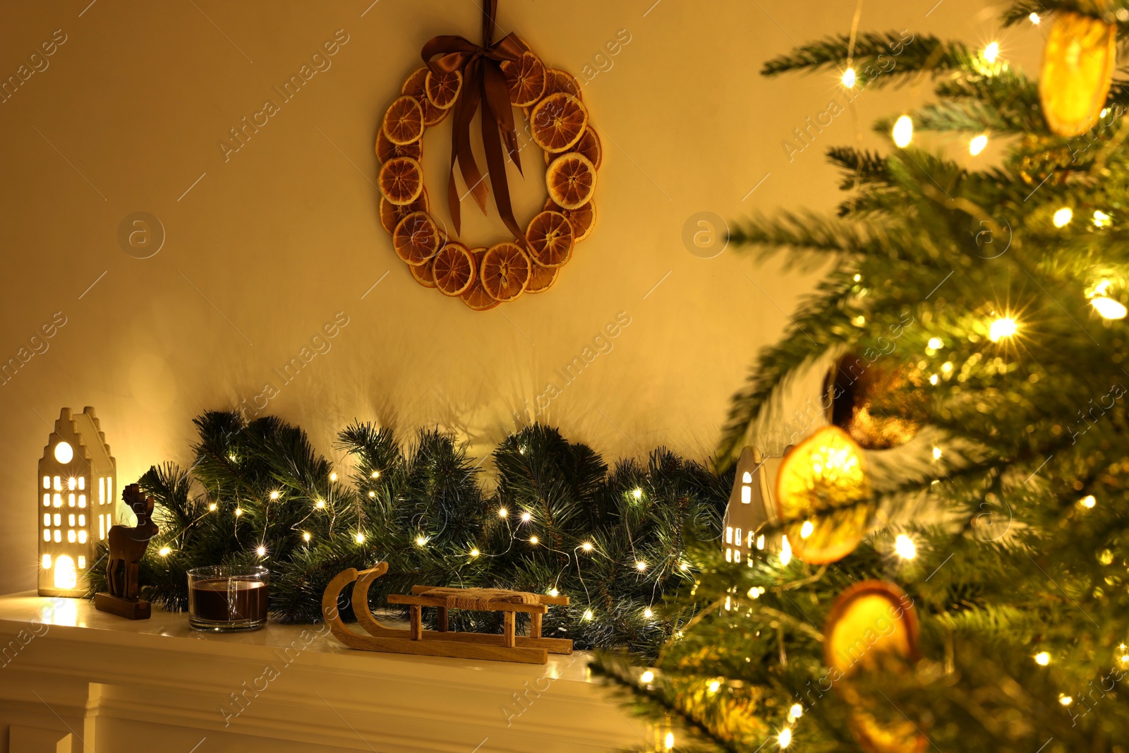 Photo of Fireplace with Christmas accessories and decorative wreath near fir tree indoors