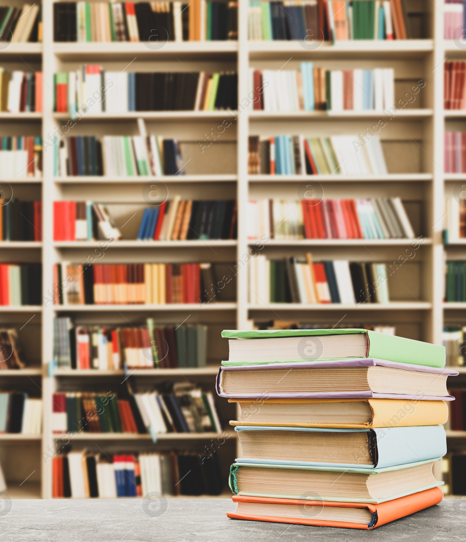 Image of Stack of colorful books on table in library, space for text  