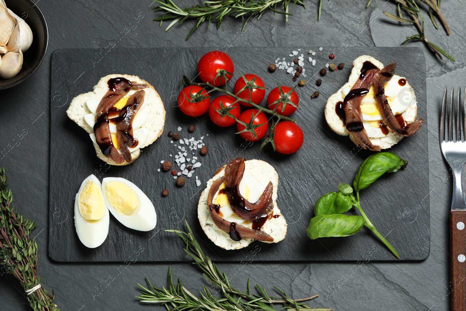 Photo of Flat lay composition with delicious anchovy sandwiches on black table