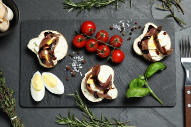 Photo of Flat lay composition with delicious anchovy sandwiches on black table