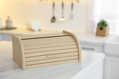 Photo of Wooden bread box on white marble table in kitchen