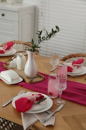 Color accent table setting. Glasses, plates, pink napkins and vase with green branch in dining room