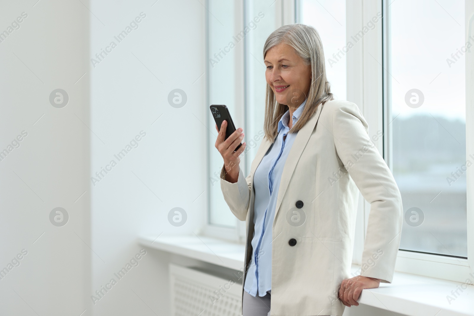 Photo of Senior woman using mobile phone at home, space for text