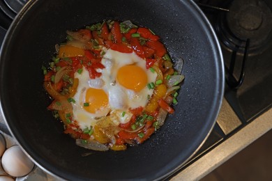 Photo of Cooking tasty eggs with vegetables in frying pan, top view