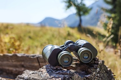 Photo of Modern binoculars on wooden surface outdoors. Camping equipment