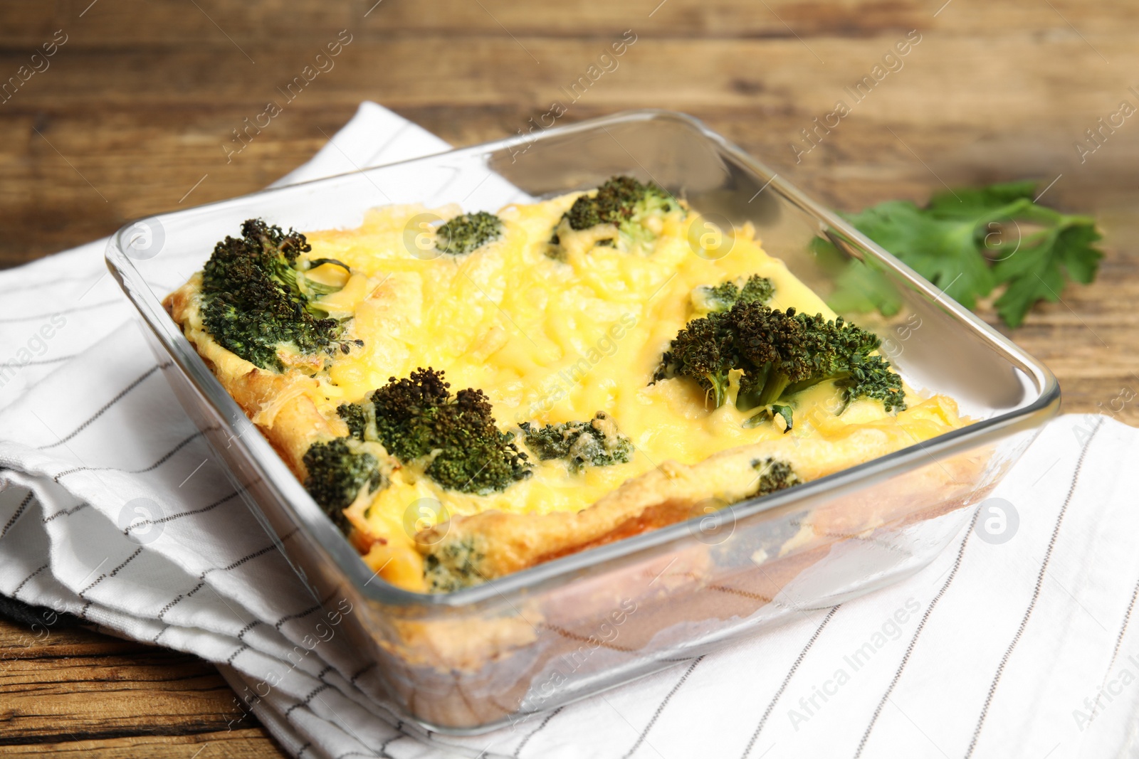 Photo of Tasty broccoli casserole in baking dish on wooden table