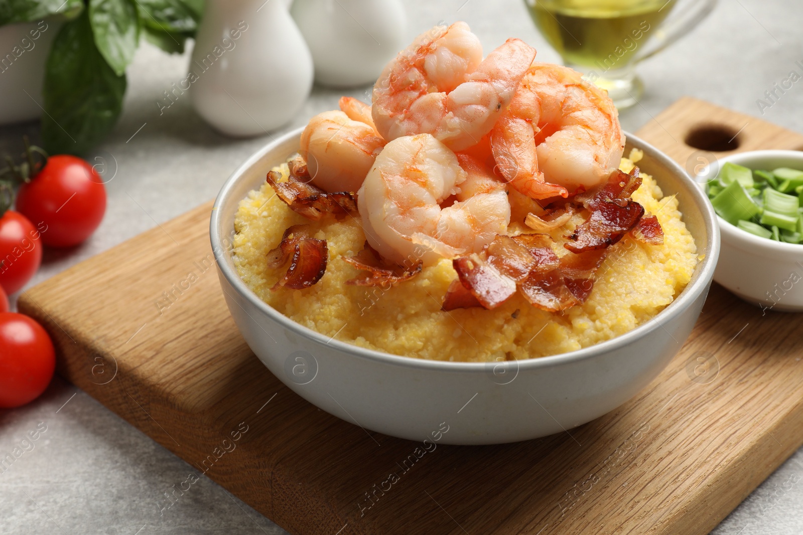 Photo of Fresh tasty shrimps, bacon and grits in bowl on table, closeup