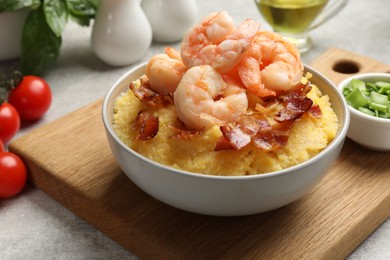 Fresh tasty shrimps, bacon and grits in bowl on table, closeup