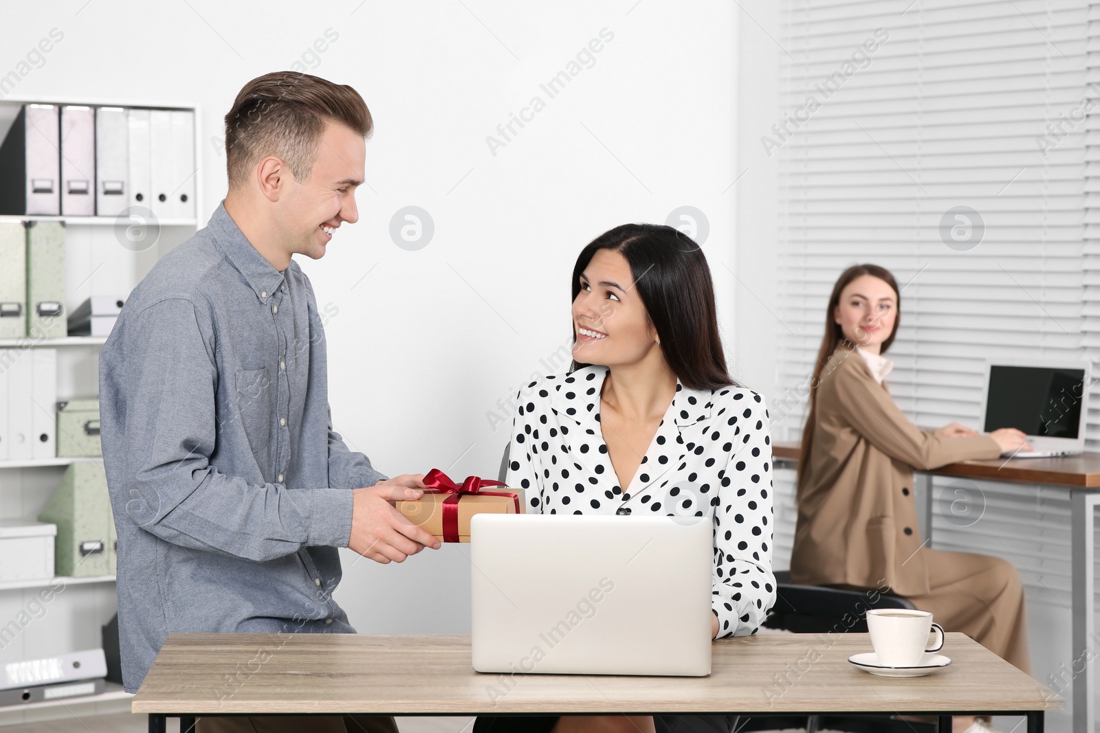 Photo of Man presenting gift to his colleague in office