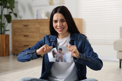 Upset woman ripping photo at home. Divorce concept